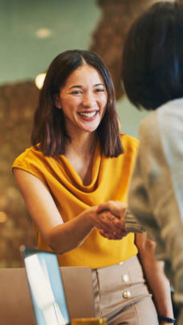 Businesswoman shaking hands with client and smiling cheerfully in meeting room Businesswoman shaking hands with client and smiling cheerfully in meeting room
